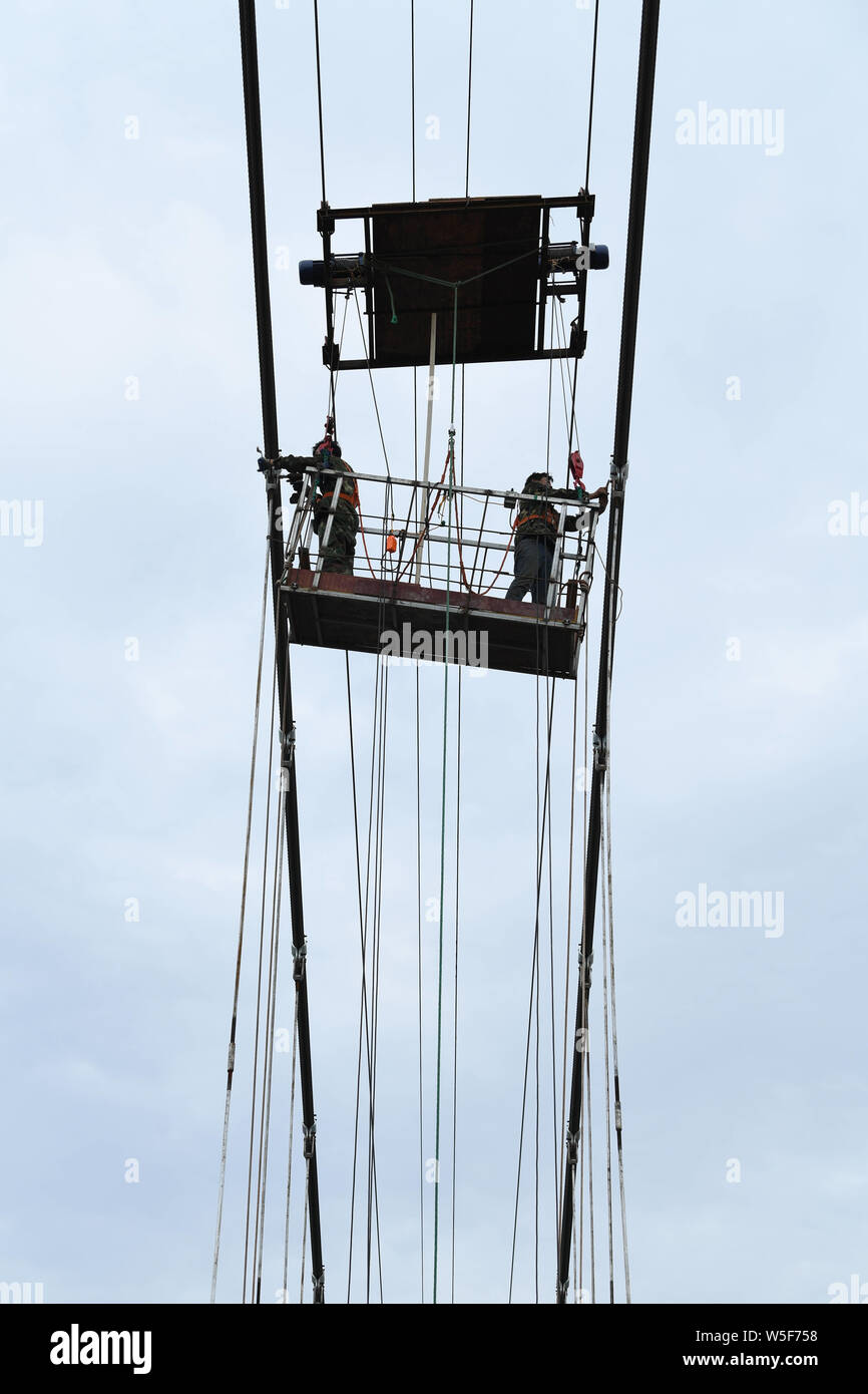 Lavoratori cinesi il lavoro in cantiere di un 260 metri colorato 7D con fondo di vetro ponte di sospensione in Nanning city, a sud della Cina di Guangxi Foto Stock