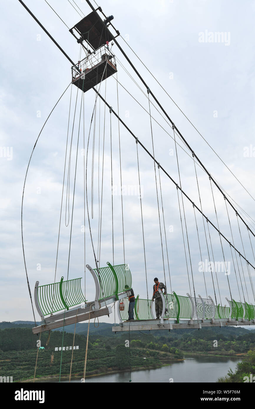 Lavoratori cinesi il lavoro in cantiere di un 260 metri colorato 7D con fondo di vetro ponte di sospensione in Nanning city, a sud della Cina di Guangxi Foto Stock