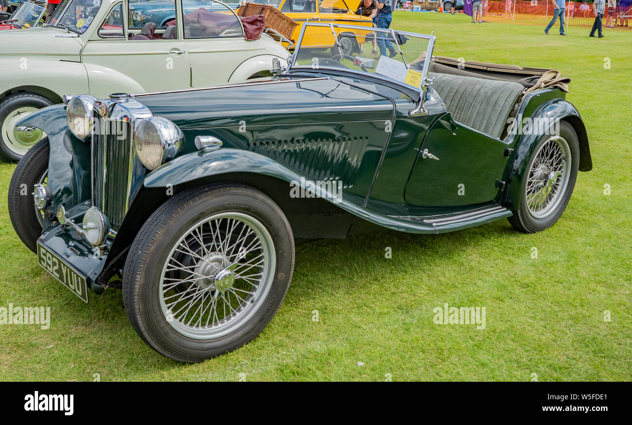 Vista laterale di un vintage convertible MG auto sportiva, in British Racing Green, sul display all'annuale classic car show a Wroxham, Norfolk, Regno Unito Foto Stock