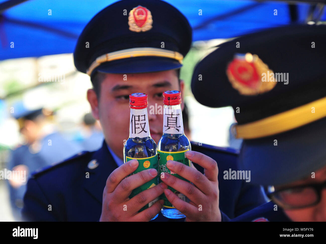 Un ufficiale cinese confronta una contraffazione di Baijiu a uno reale sul mondo dei diritti del consumatore giorno, spesso indicati come '315' in Cina, in Nanning ci Foto Stock