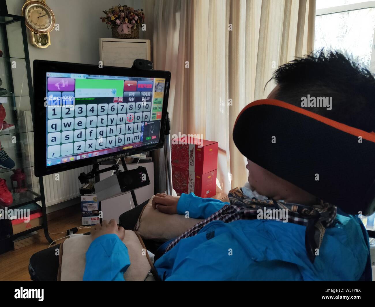 Il 35-anno-vecchio uomo cinese negli ultimi stadi di sclerosi laterale amiotrofica (ALS) utilizza il computer speciale nella sua casa a Pechino, 12 marzo 20 Foto Stock
