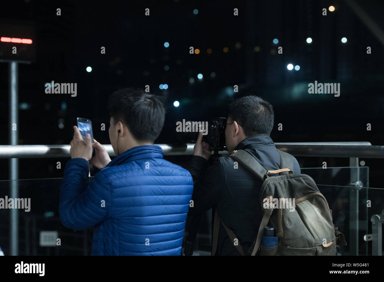 I passeggeri di scattare delle foto di un treno della metropolitana a correre verso la stazione di Haitangxi sulla linea Loop di Chongqing Rail Transit in notturna a Chongqing Cina Foto Stock