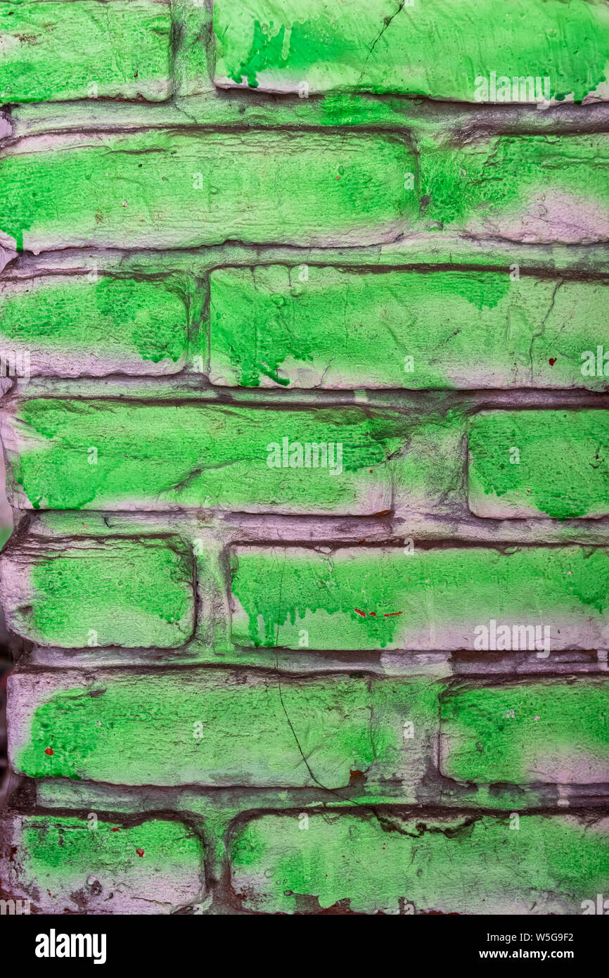 Dipinto di verde il vecchio muro di mattoni con base bianca, semplice graffiti, sfondo o texture con ruvida cercando lavoro di vernice Foto Stock