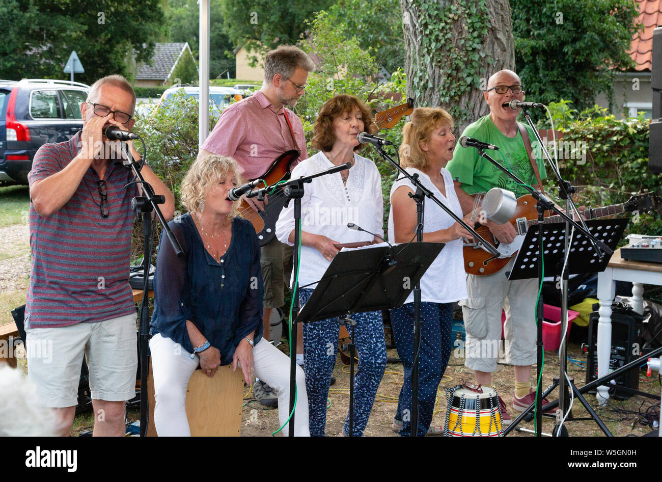 Retirement Lifestyle; una band musicale di un gruppo di anziani pensionati maturi di 60s anni che cantano come hobby in pensione, giocando all'aperto, Cambridgeshire UK Foto Stock