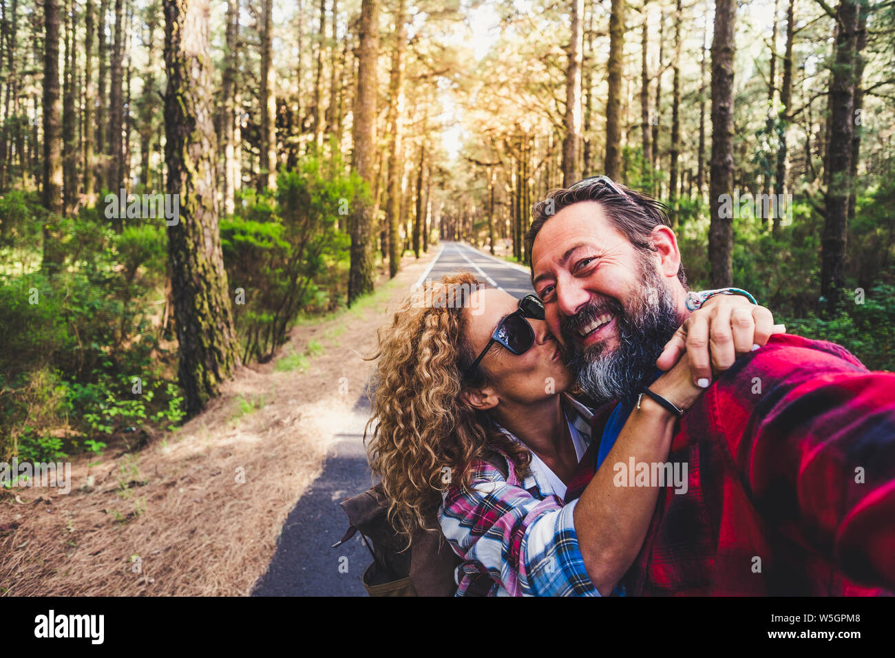 Gente allegra bella cacuasian adulto giovane godendo outdoor le attività per il tempo libero in viaggio nella foresta e baciare ogni altra con divertimento e happine Foto Stock