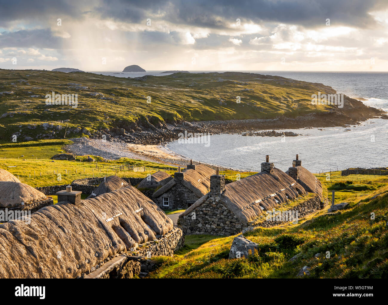 Gearrannan, Shottland- Giugno 20, 2018: Gearrannan blackhouse villaggio con case dai tetti di paglia sull isola di Lewis in un dorato della luce della sera Foto Stock