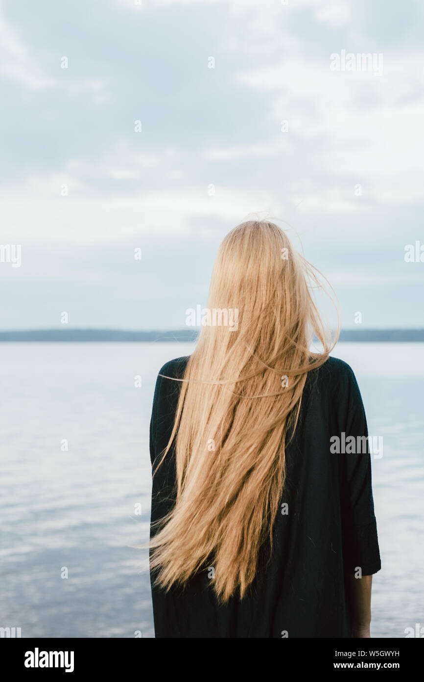 Capelli lunghi donna che guarda al lago sul giorno di estate Foto Stock