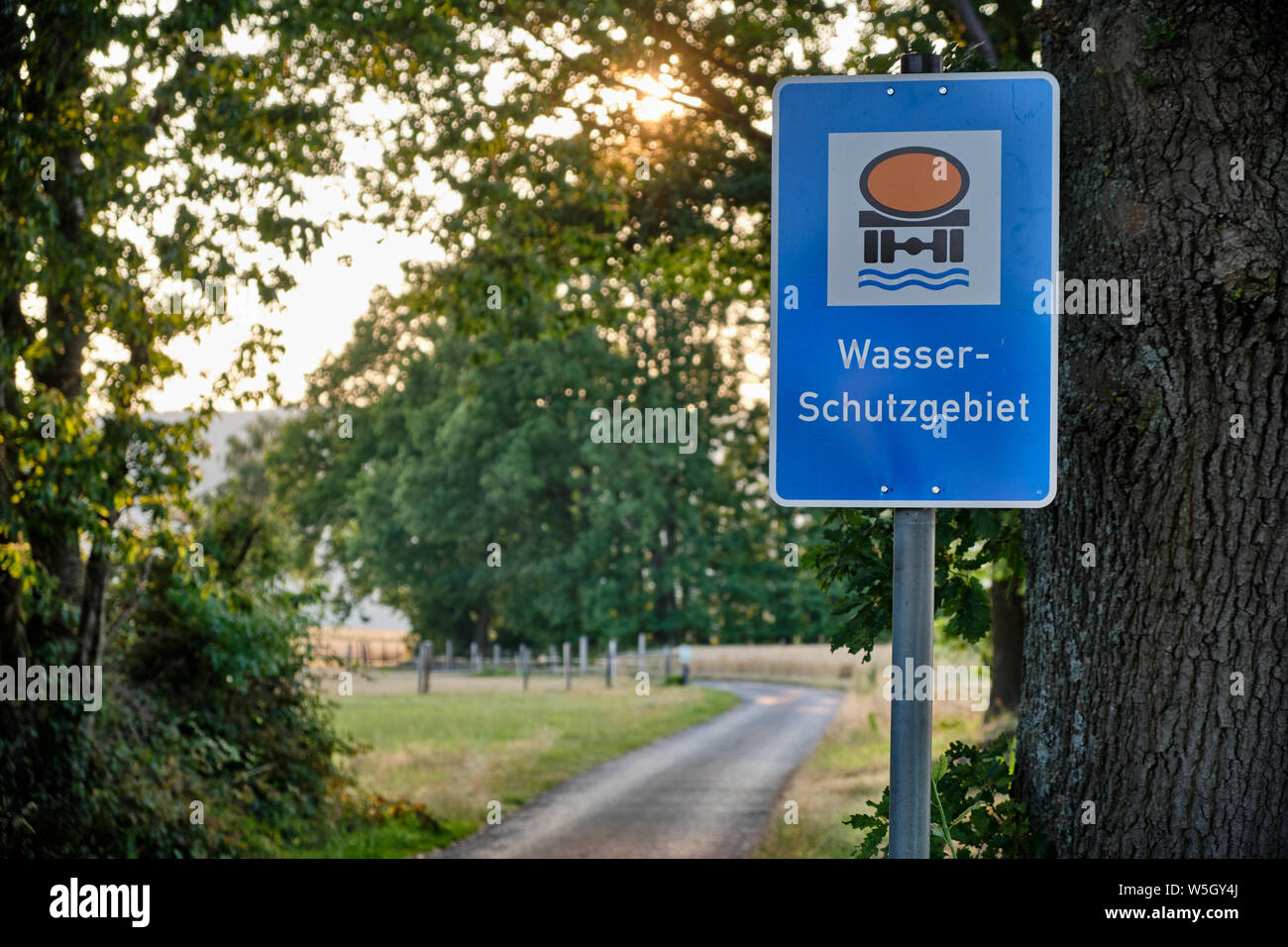 Bad Orb Germania - Luglio 17, 2019: un segno blu in un paesaggio di campagna con bellissimi alberi e una strada dicendo che si tratta di un 'Wasserschutzgebiet' Foto Stock