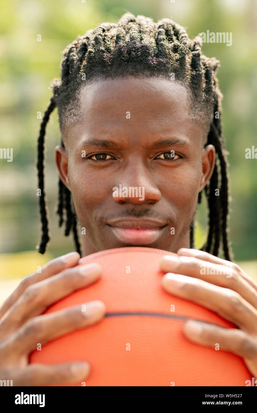 Giovane giocatore di pallacanestro professionale tenendo la sfera con il suo volto Foto Stock