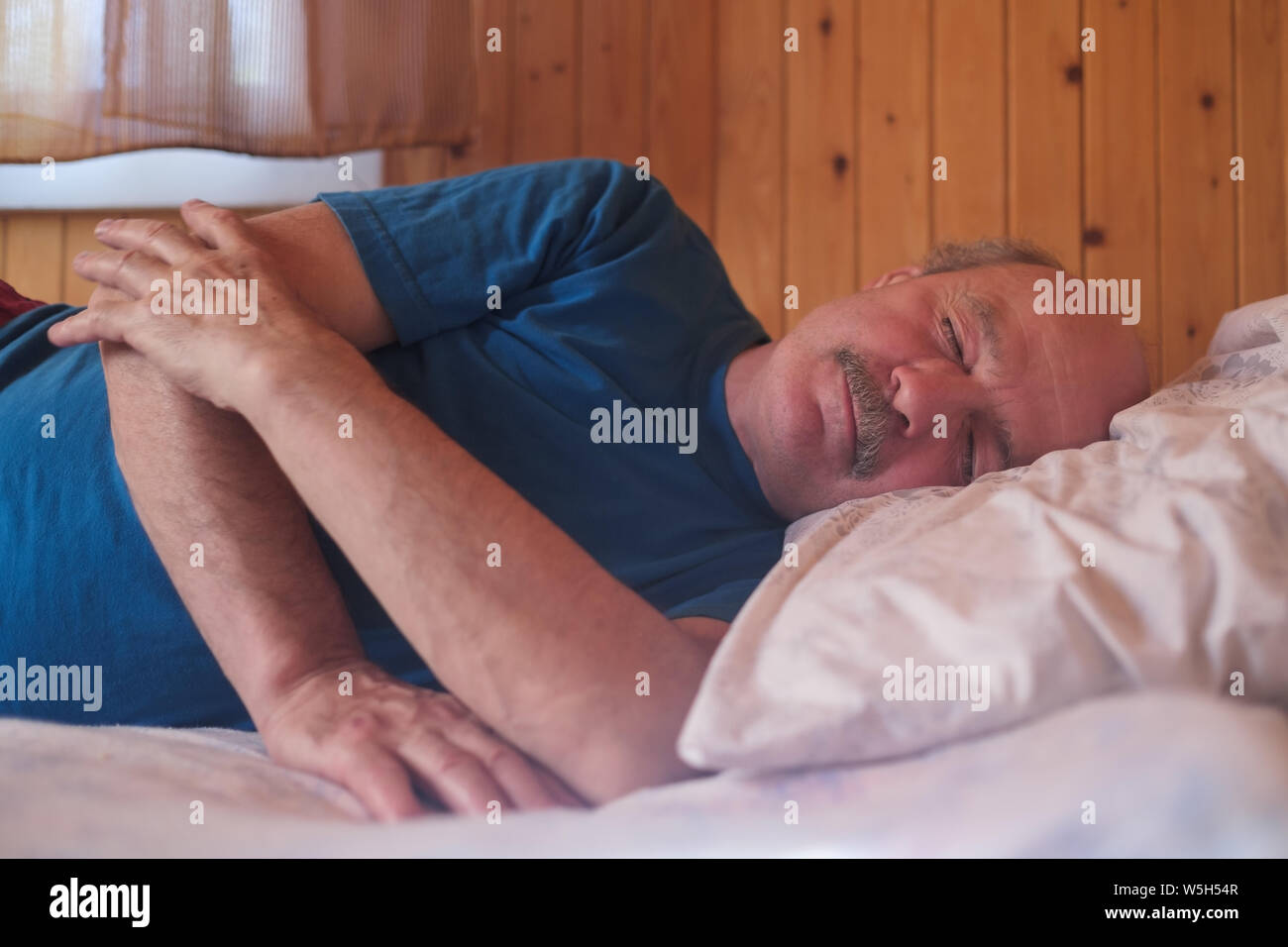 Senor uomo dorme sul letto di casa. Close up. Foto Stock