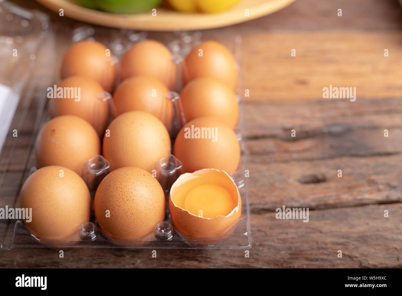 Uova di pollo e tuorlo d'uovo con rotti nella scatola di plastica sul tavolo di legno. Uova di gallina sono ricche in proteina di elevata qualità che è efficace nell'assorbimento. Foto Stock