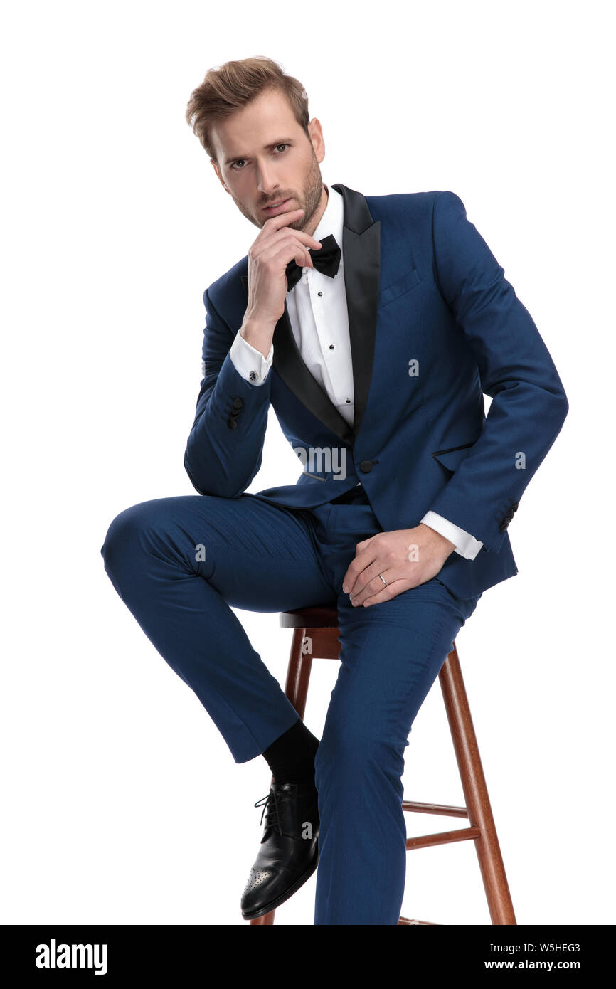 Uomo bello in costume blu è il pensiero mentre è seduto su un seggiolino su  sfondo bianco Foto stock - Alamy