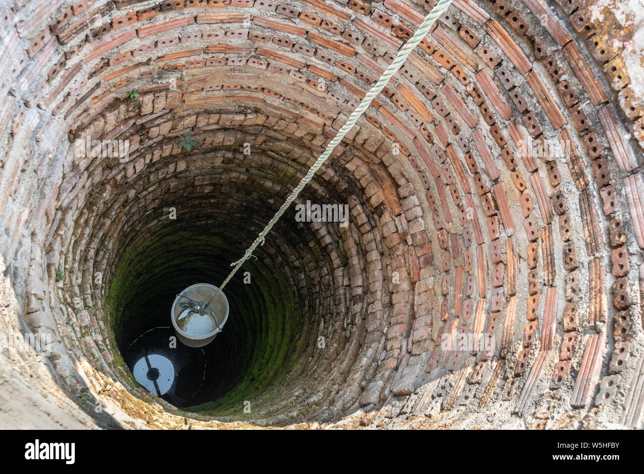 Secchio di plastica nella vecchia antiche acque sotterranee bene. vintage pozzi artesiani. Foto Stock