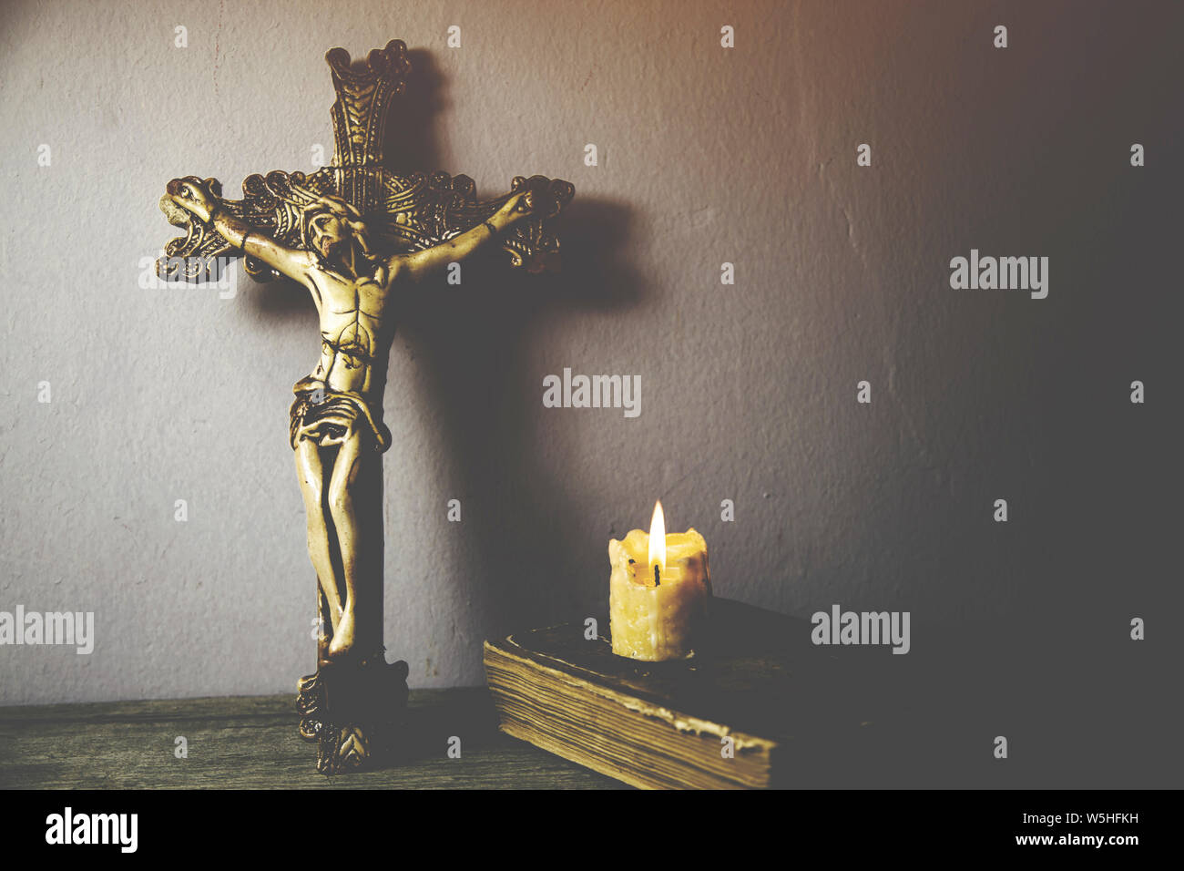 Croce, libro e candela su sfondo di legno Foto Stock