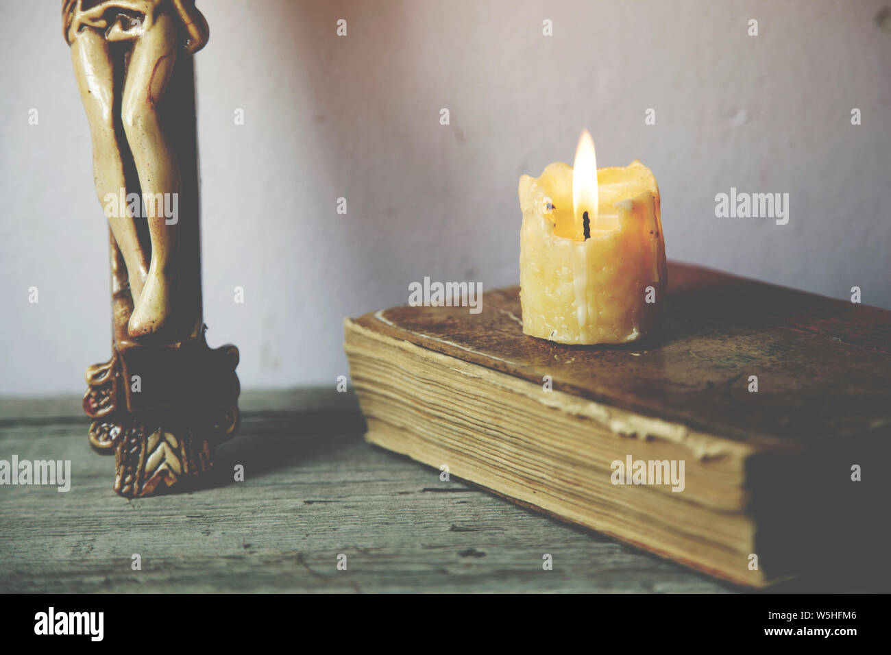 Croce, libro e candela su sfondo di legno Foto Stock