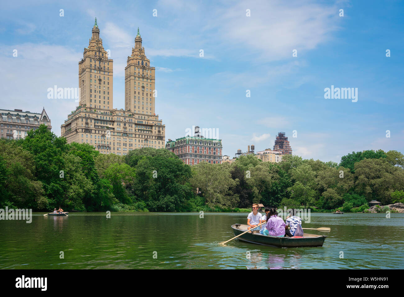 New York park, vista in estate di persone imbarcazioni a remi su Central Park Lake con il San Remo edificio in background, Manhattan, New York City, Stati Uniti d'America. Foto Stock