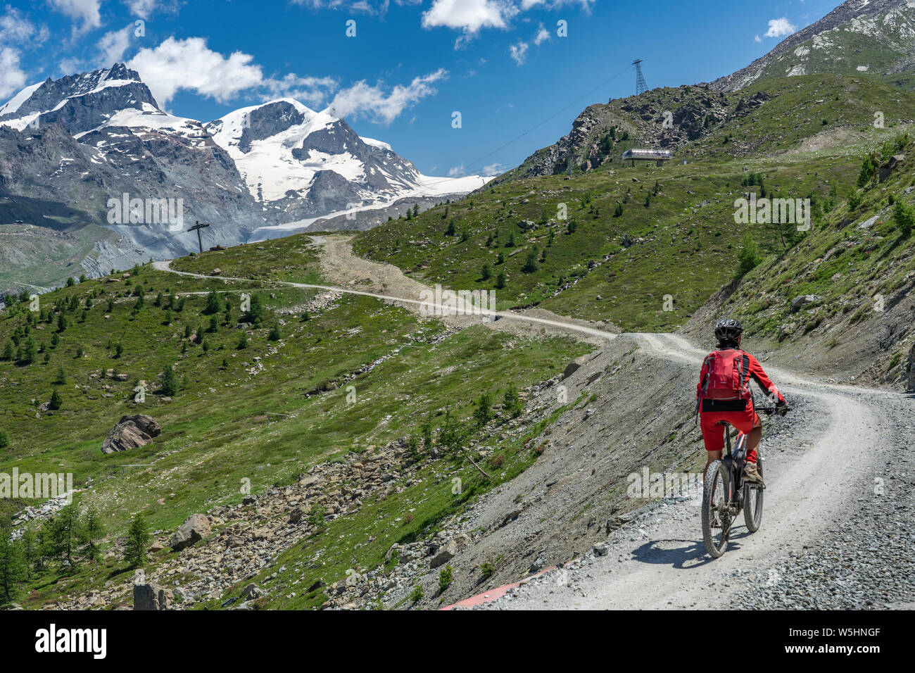Attiva donna senior, cavalcando la sua mountainbike elettrico sotto il famoso Gornergrat in Zermatt, in background e Rimpfischhorn Strahlhorn,Wallis,sw Foto Stock