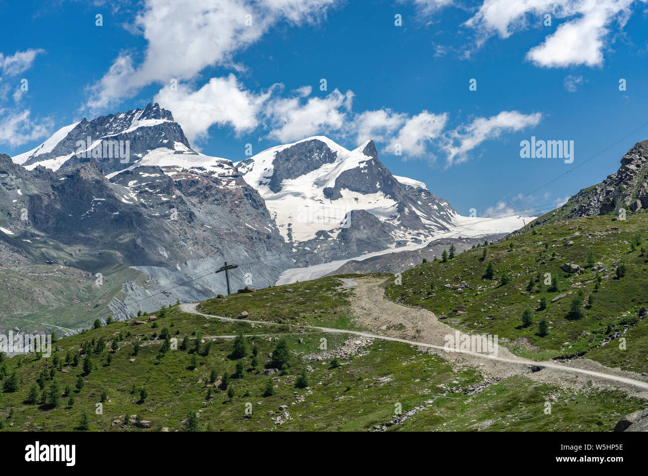 Attiva donna senior, cavalcando la sua mountainbike elettrico sotto il famoso Gornergrat in Zermatt, in background e Rimpfischhorn Strahlhorn,Wallis,sw Foto Stock