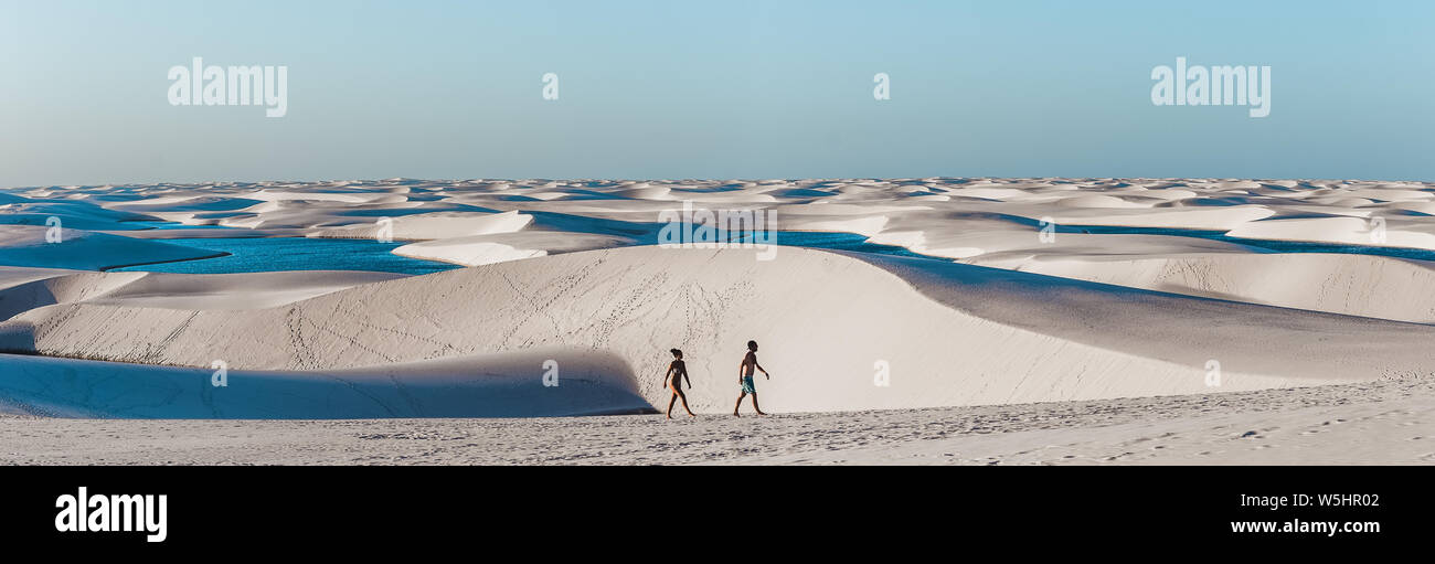 Coppia di viaggio trek attraverso gigantesche dune di sabbia con le lagune di Lençóis Maranhenses, uno dei più incredibili attrae turisti nel nord-est del Brasile Foto Stock