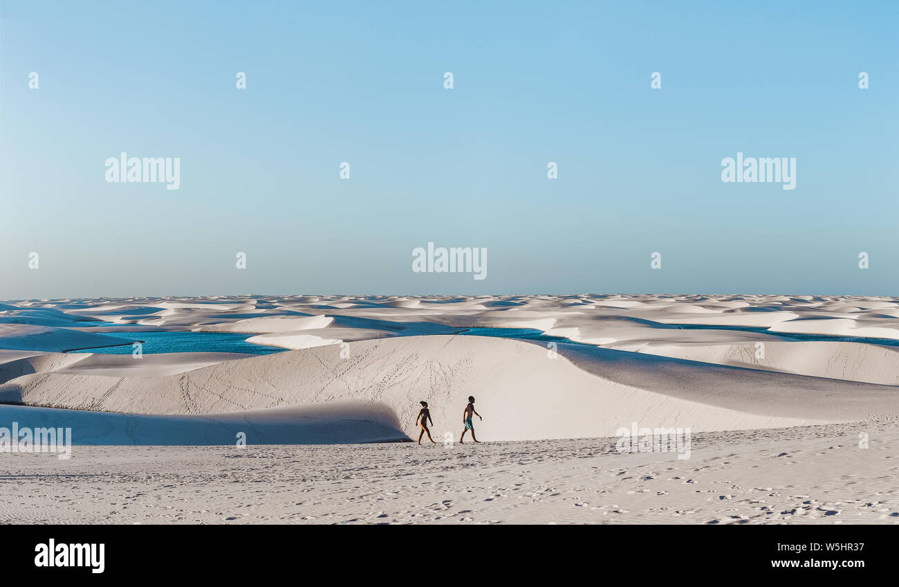 Coppia di viaggio trek attraverso gigantesche dune di sabbia con le lagune di Lençóis Maranhenses, uno dei più incredibili attrae turisti nel nord-est del Brasile Foto Stock