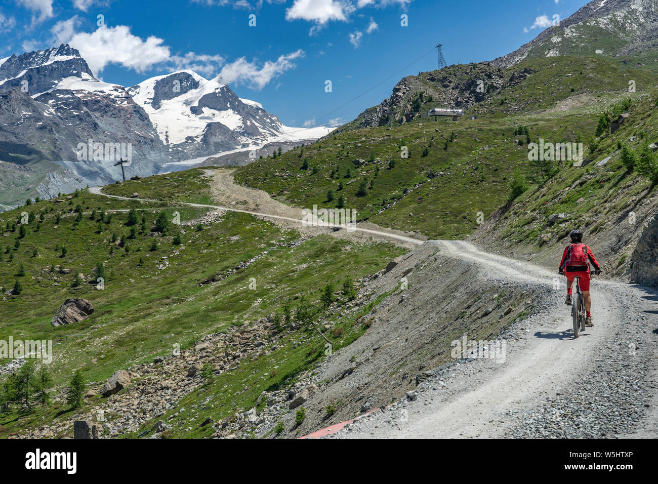 Attiva donna senior, cavalcando la sua mountainbike elettrico sotto il famoso Gornergrat in Zermatt, in background e Rimpfischhorn Strahlhorn,Wallis,sw Foto Stock