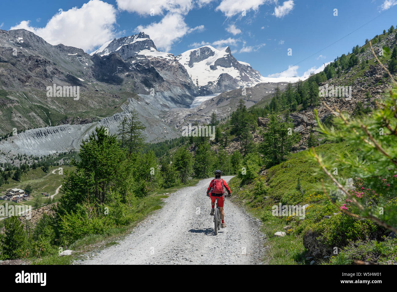 Attiva donna senior, cavalcando la sua mountainbike elettrico sotto il famoso Gornergrat in Zermatt, in background e Rimpfischhorn Strahlhorn,Wallis,sw Foto Stock