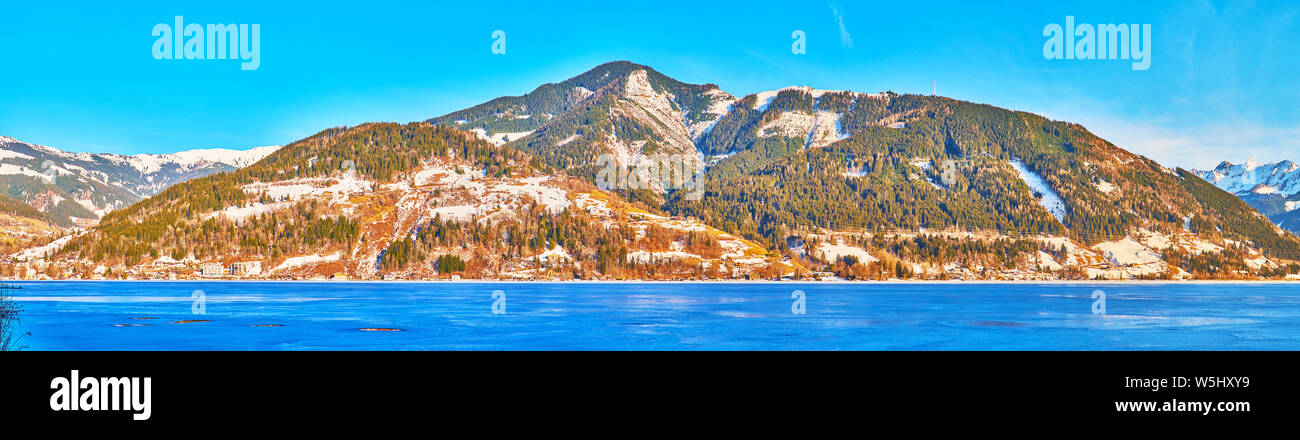 Panorama della catena montuosa alpina dietro il blu superficie ghiacciata del lago Zeller See, Zell am See, Austria Foto Stock