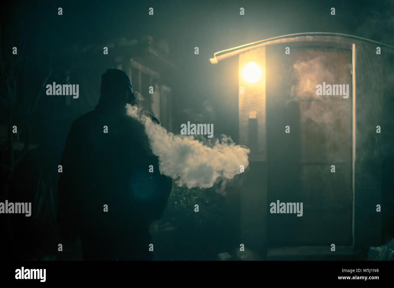 Strano uomo di fumare durante la notte con grande effetto di vapore dalla sigaretta Foto Stock