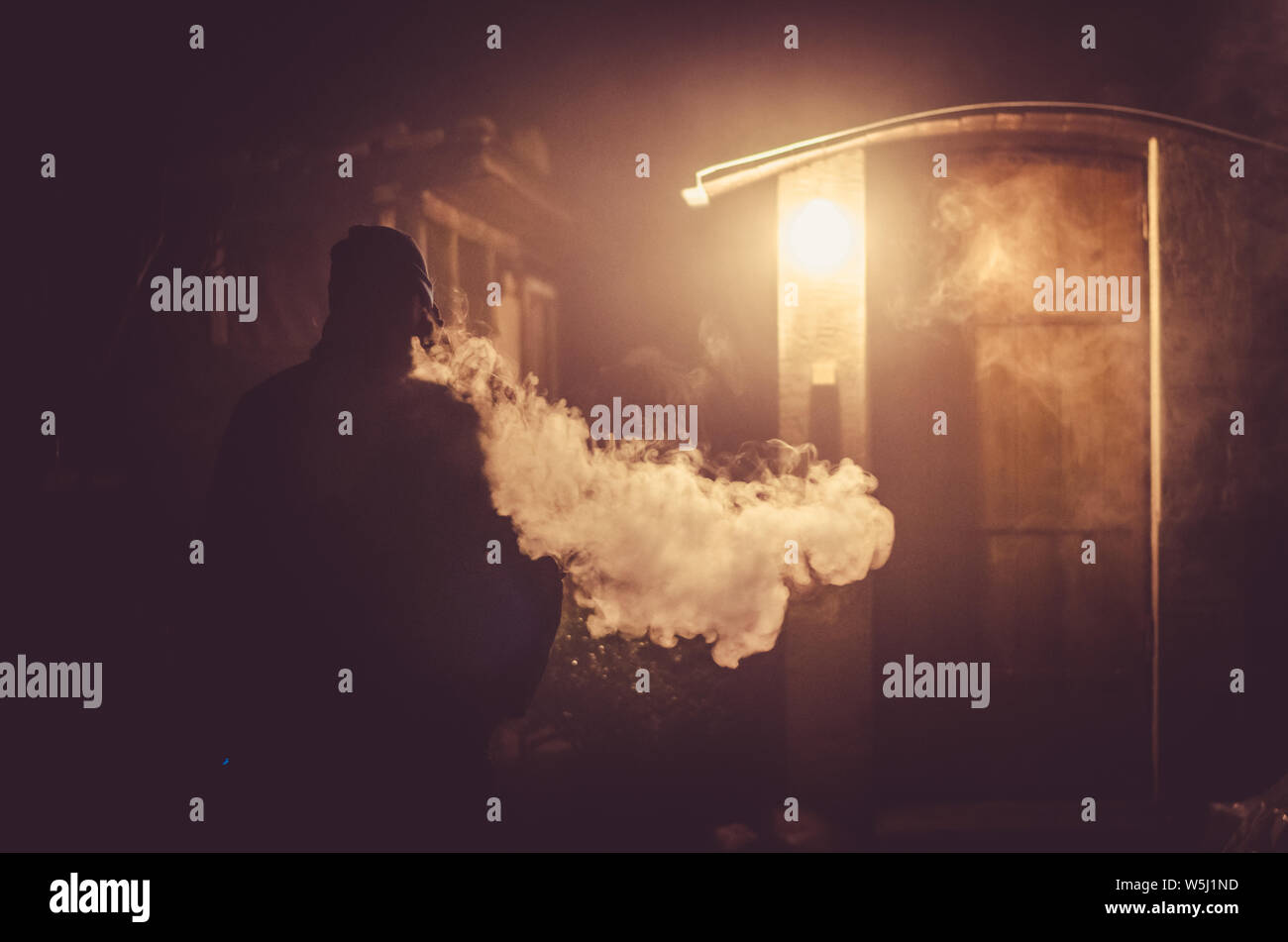 Strano uomo di fumare durante la notte con grande effetto di vapore dalla sigaretta Foto Stock