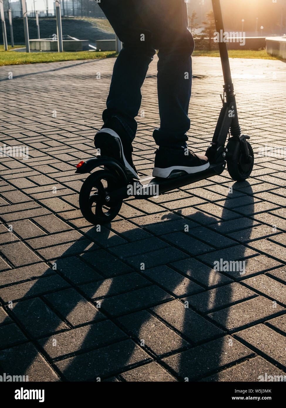 Vista ravvicinata di gambe di uomo su scooter elettrico all'esterno. Foto Stock