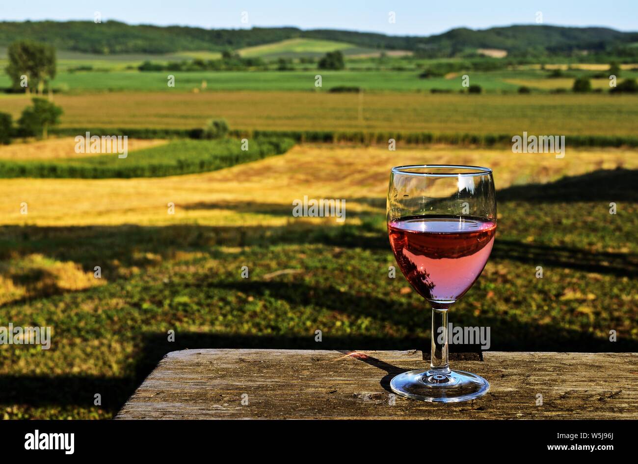 Un bicchiere di vino rosato con belle rurale di fondo Foto Stock