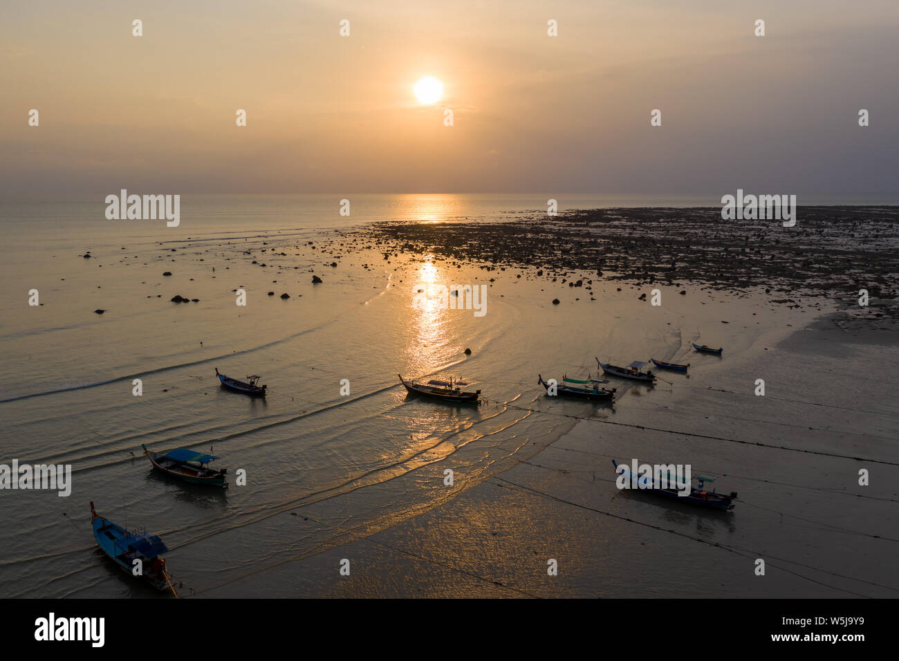Antenna fuco vista del tramonto su un poco profondo, oceano tropicale con legno tradizionali barche longtail al di ancoraggio Foto Stock