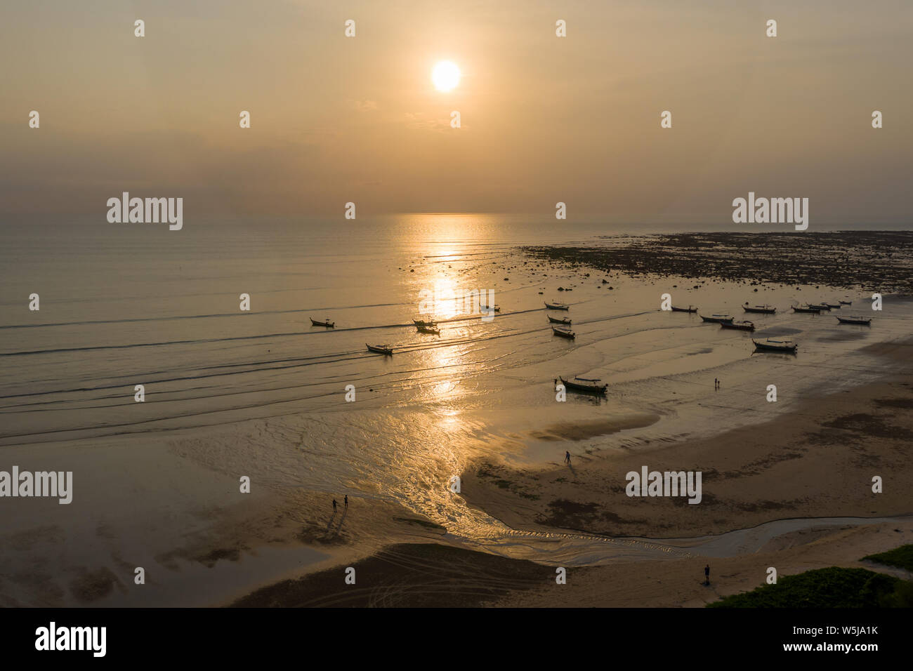 Antenna fuco vista del tramonto su un poco profondo, oceano tropicale con legno tradizionali barche longtail al di ancoraggio Foto Stock