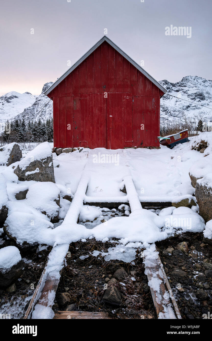 Una tradizionale barca norvegese casa con scalo in invernale e neve in Isole Lofoten in Norvegia Foto Stock