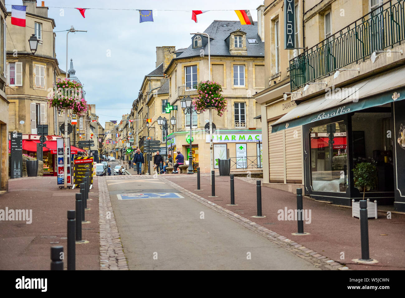 Turisti e locali francese a piedi lungo una strada rue Saint-Jean main street passato caffetterie e negozi in Normandia città di Bayeux, Francia Foto Stock