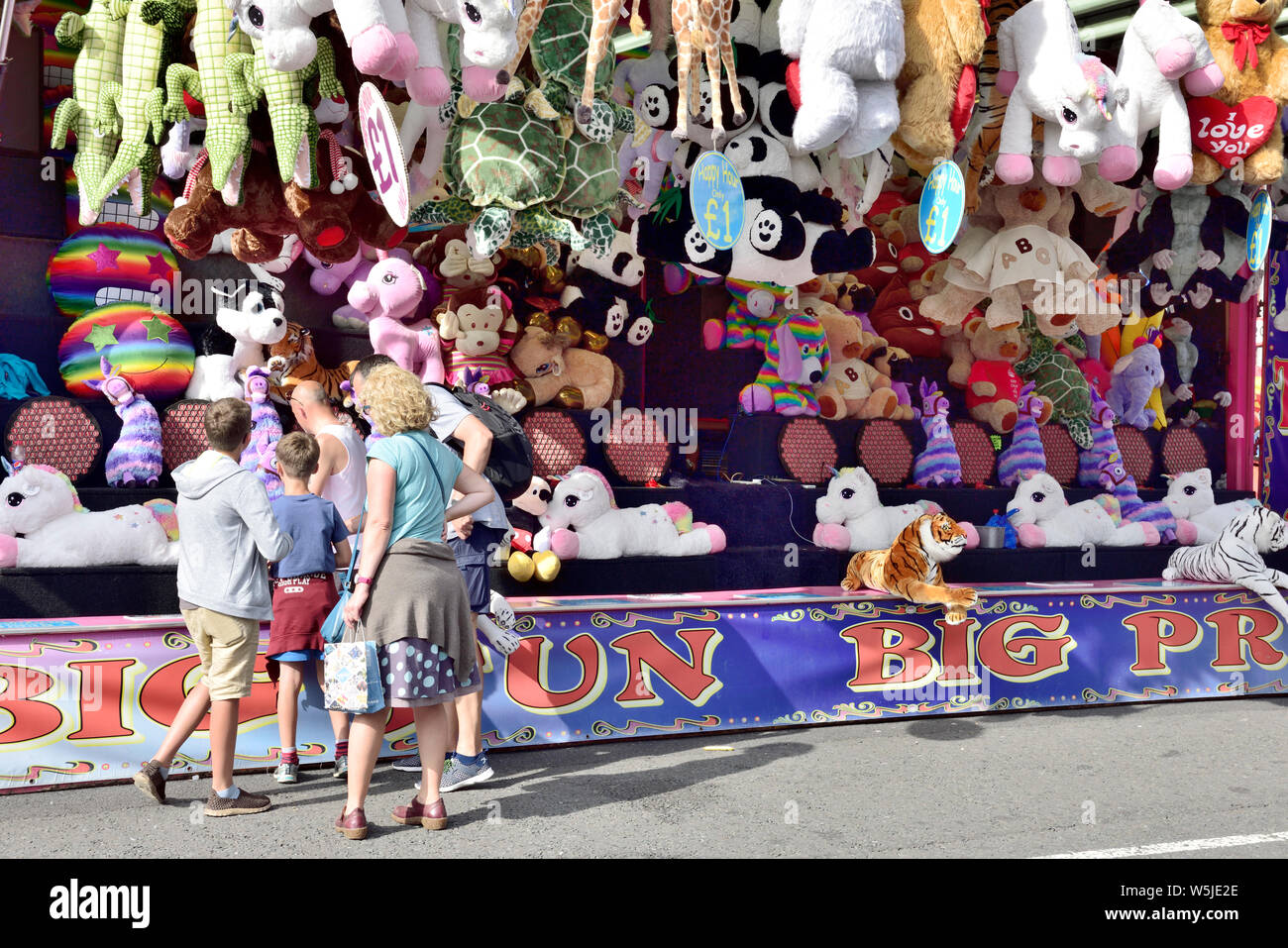 Famiglia con bambini al parco di divertimenti in stallo a lanciare freccette a bordo per vincere coccola giocattoli. Il porto di Bristol festival, REGNO UNITO Foto Stock