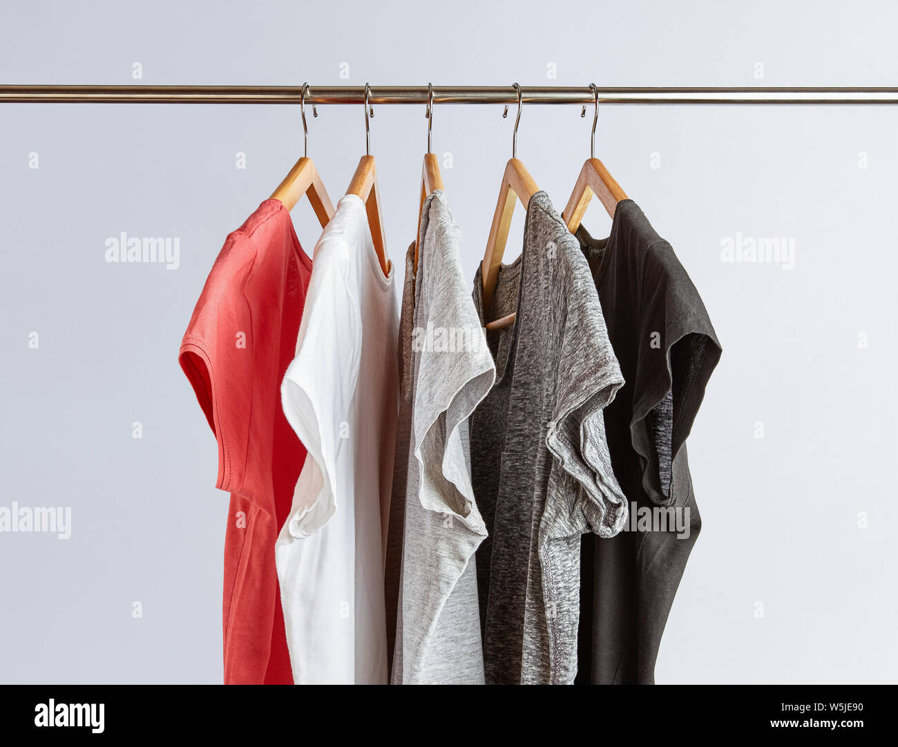 Capsula concetto guardaroba. T-shirt in tonalità di colori neutri e appeso su un rack di abbigliamento. Guardaroba minimalista. Foto Stock