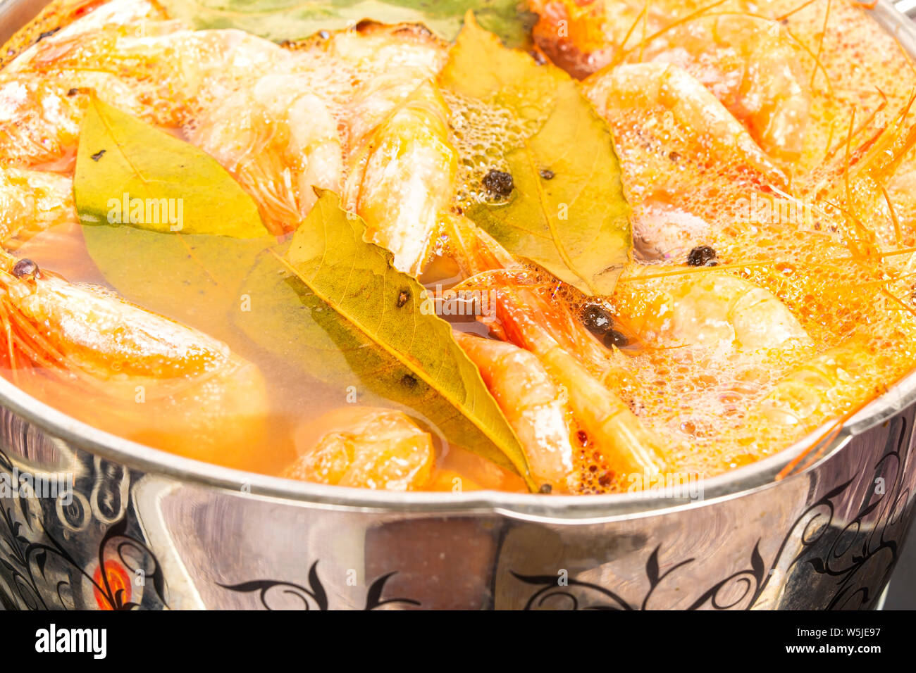 Atlantic i gamberetti sono cotti con la foglia di alloro e il pepe della Giamaica in un piatto di pesata in acciaio inox. Foto Stock