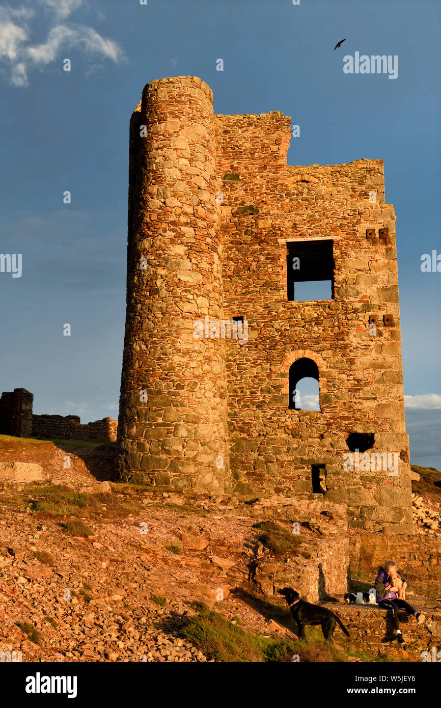 Ragazza con i cani e il cucciolo di rovine di timbri e Capriccio casa del motore in corrispondenza di Wheal Coates rebbio miniera in luce rossa al tramonto Cornwall Inghilterra Foto Stock