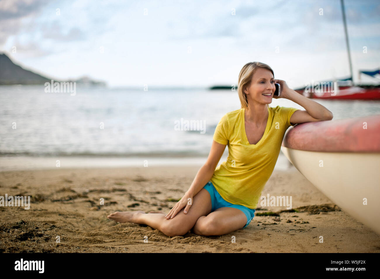 Metà donna adulta parlando al cellulare sulla spiaggia durante le sue vacanze estive. Foto Stock