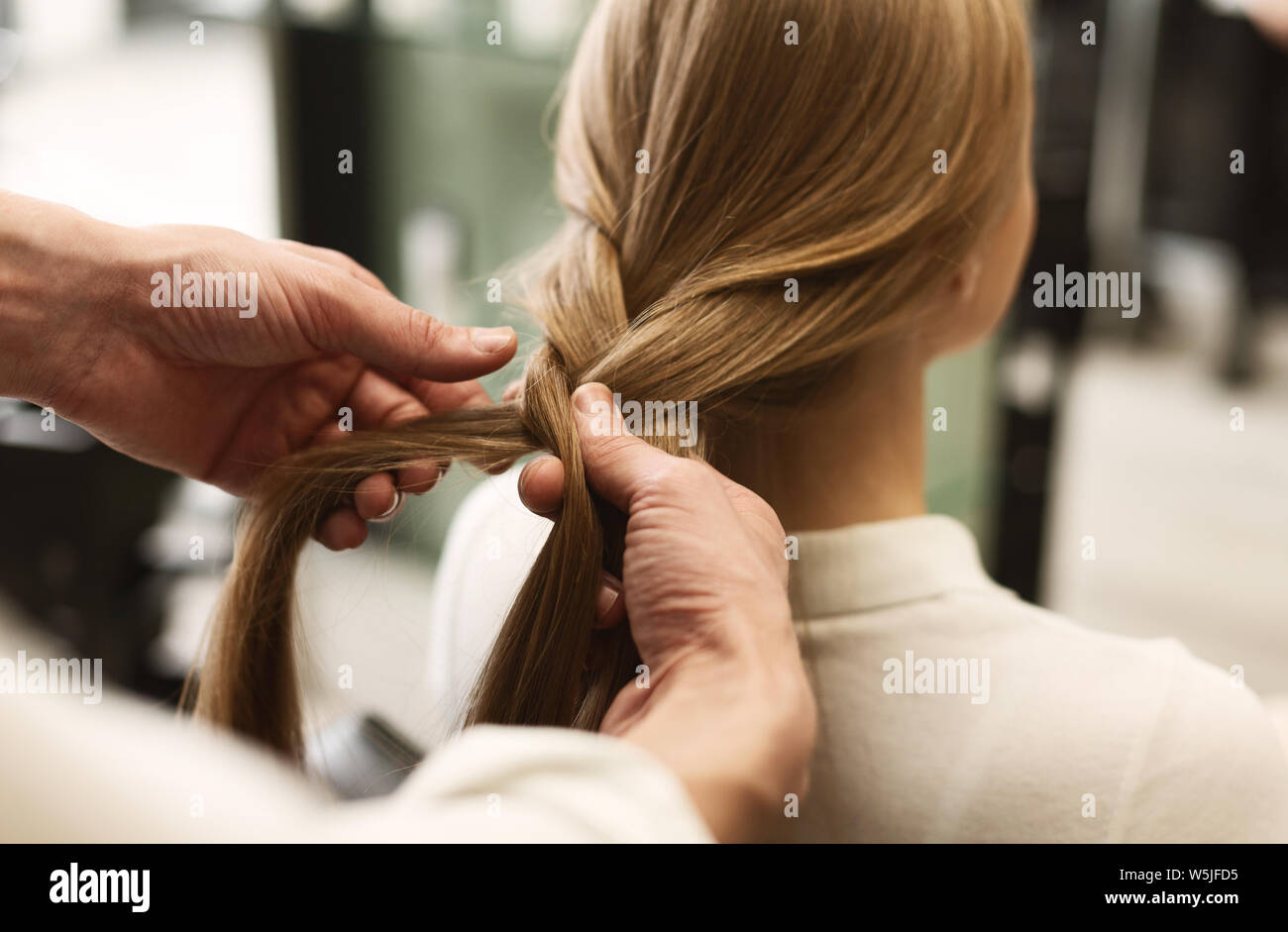 La stilista trecciatura ai capelli della ragazza in studio di bellezza, Primo Piano Foto Stock