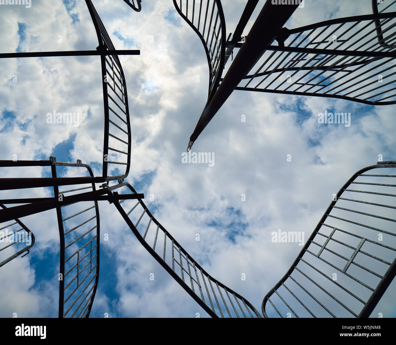 Una vista dalla terra alla ricerca fino al cielo blu e nuvole intersecate da barricate che formano la scultura "mente aperta" per artista Yoan Capote Foto Stock