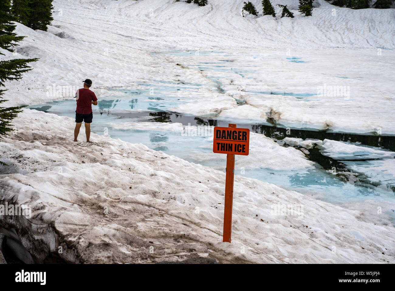 Lassen National Park, California - Luglio 9, 2019: Turistica ignorando chiaramente il pericolo ghiaccio sottile segno di avvertimento sul Lago Smeraldo, concetto per incidenti in N Foto Stock