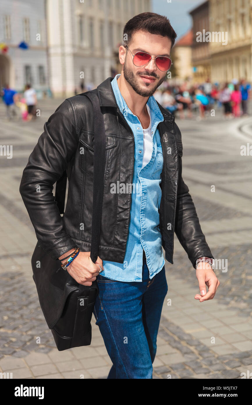 Ritratto di giovane uomo informale indossando giacca di pelle rossa e  occhiali da sole passeggiando per la città Foto stock - Alamy