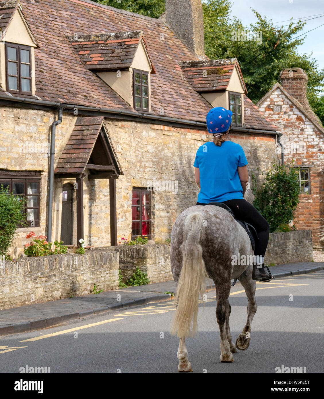 Una donna su un cavallo nel pittoresco villaggio di Bretforton, Worcestershire, England, Regno Unito Foto Stock