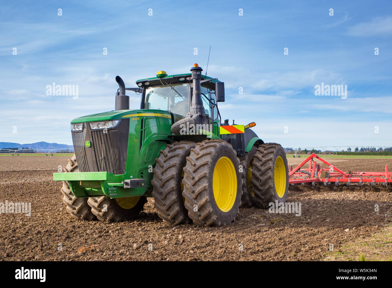 Sheffield, Canterbury, Nuova Zelanda, 27 Luglio 2019: un grande e moderno trattore John Deere rimorchia un coltivatore in un campo in inverno Foto Stock