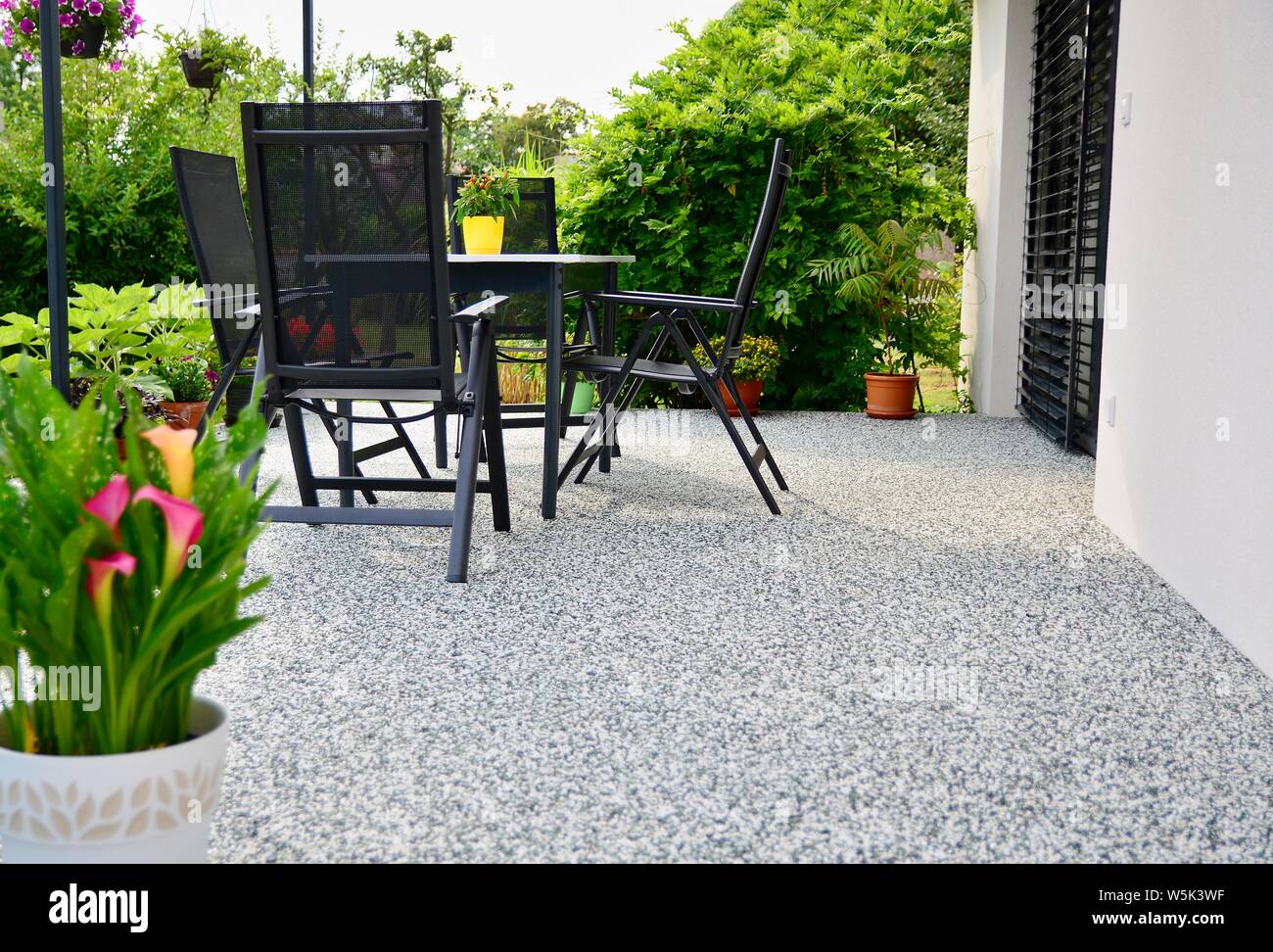 Bella terrazza con decorativi in pietra naturale pavimento, vasi di fiore e tavolo con sedie. Foto Stock