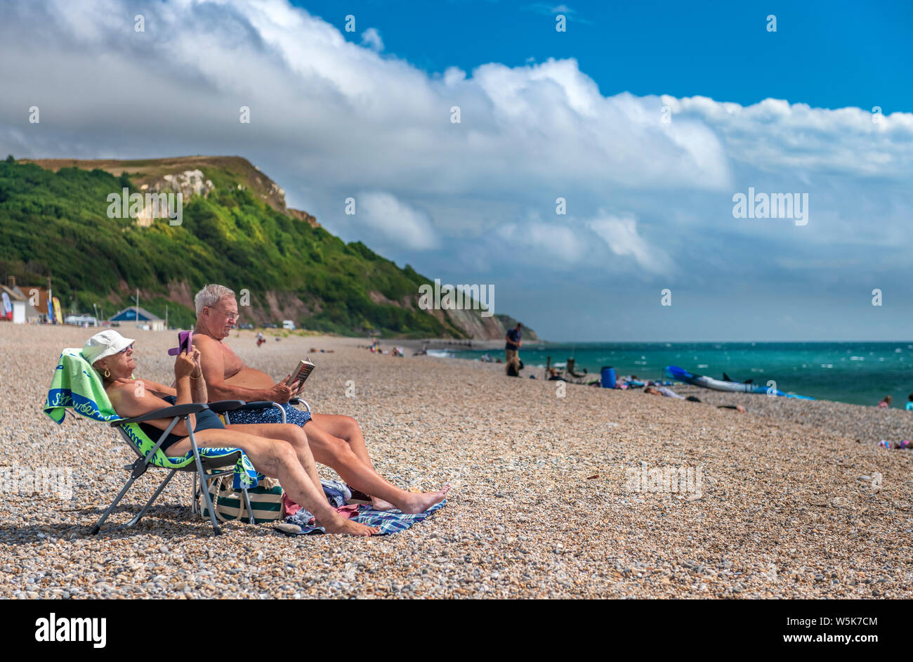 A fine luglio, un paio di rilassarsi sulla spiaggia a Seaton in South East Devon. Foto Stock