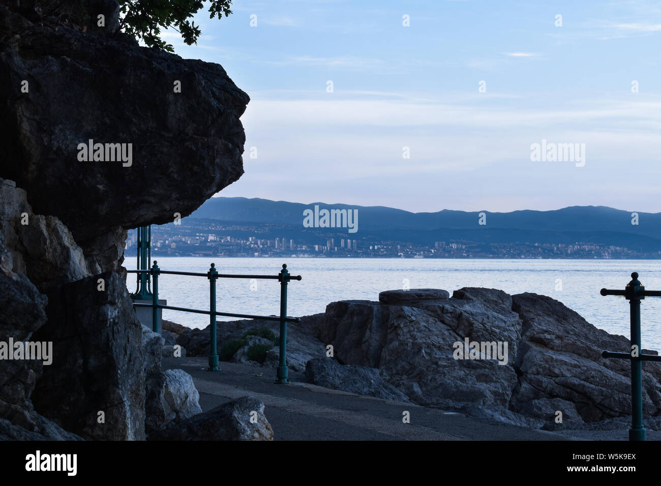 Twilight seascape dalla riviera di Opatija in Croazia. Vista della Città di Fiume. Sfumature di blu scuro, con vista sul mare dalla costa. Foto Stock