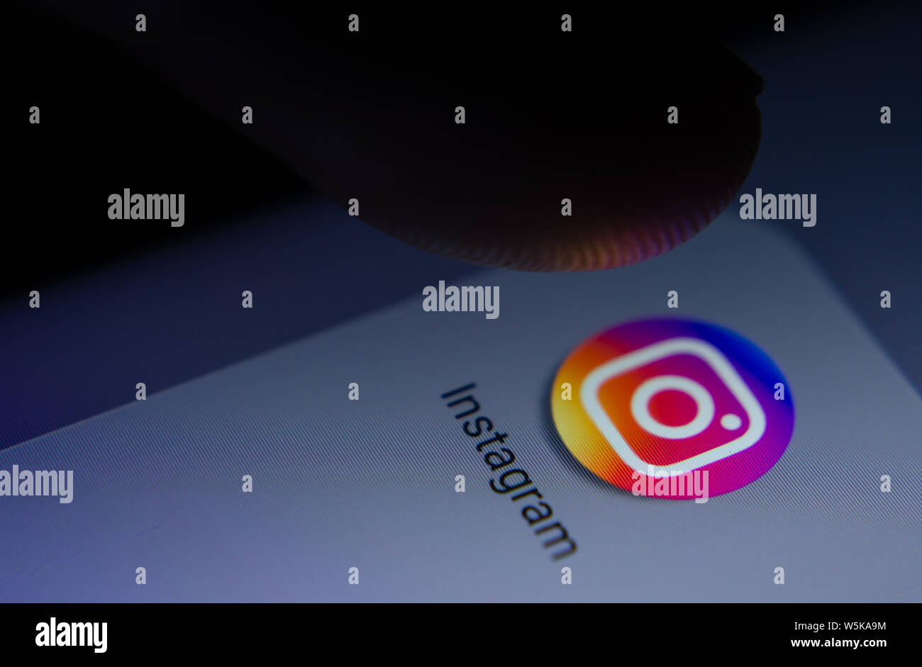 Instagram app icona sulla schermata dello smartphone con pixel visibili e il dito per lanciare. Foto Stock